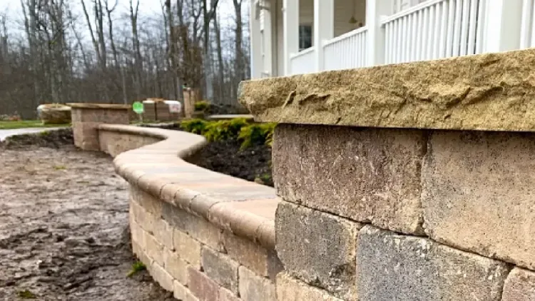 Natural stone block retaining wall with custom caps in front yard