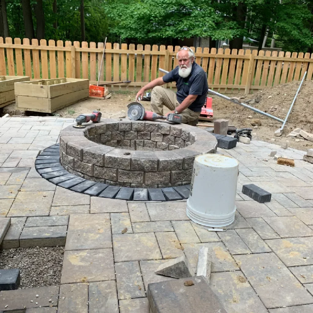 Custom circular fire pit installation on a stone paver patio with masonry block under construction.