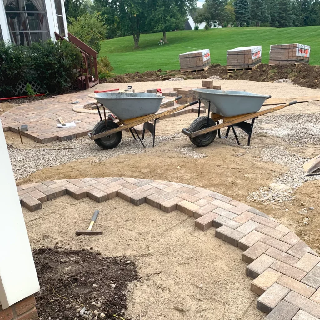 Patio construction project in progress with custom cut stone and brick being laid in full hardscape installation.