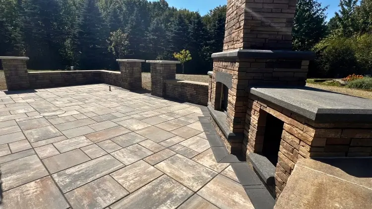 A beautiful paver patio, complete with a gas fireplace and seating wall built by Carmel Landscapes hardscape contractor.
