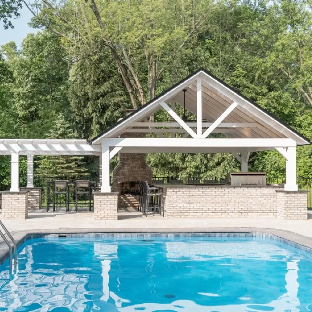 Pergola and pavilion built for pool deck with full patio, outdoor fireplace, and bar seating area.