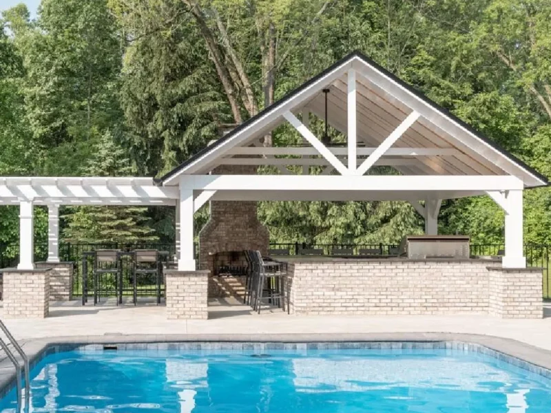 Pergola and pavilion built for pool deck with full patio, outdoor fireplace, and bar seating area.