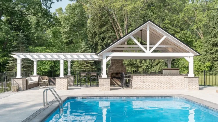 Pergola and pavilion covering outdoor kitchen and dining area on a pool deck.