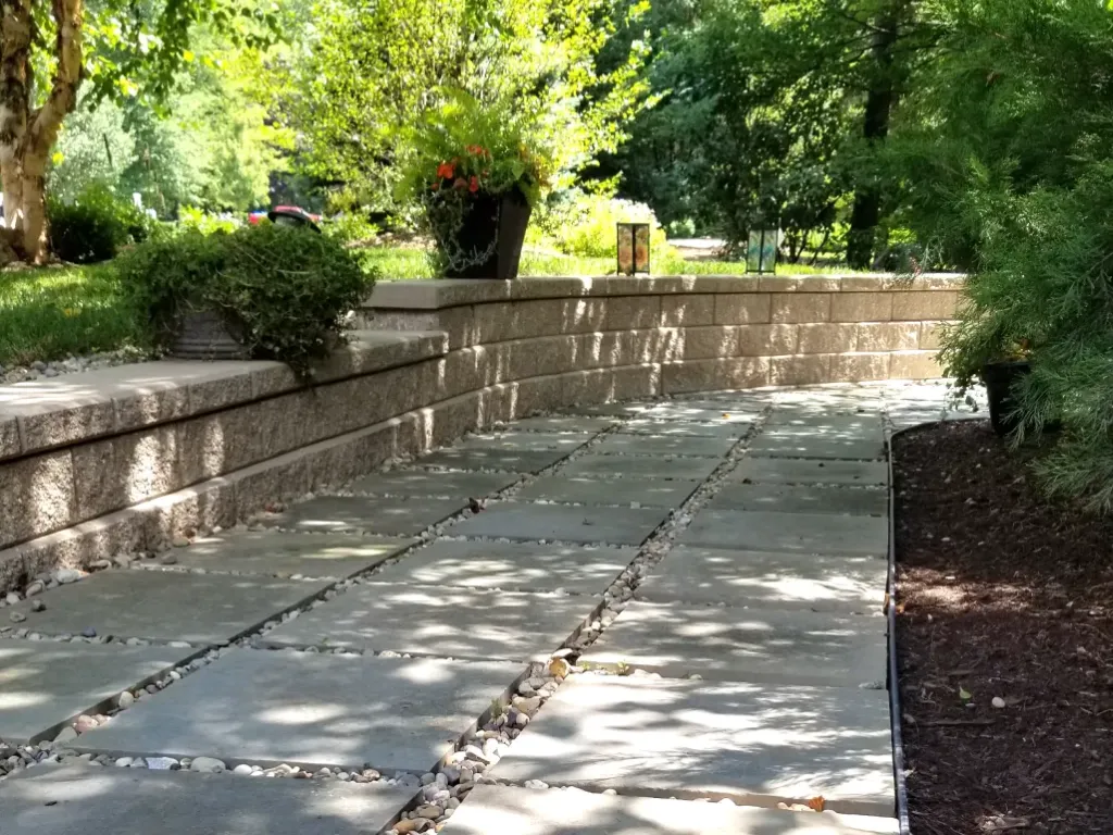 Completed retaining wall with integrated seating and stone pathway in Northeast Ohio, showing tiered outdoor living space by Carmel Landscapes