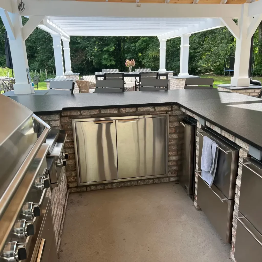 new completed outdoor kitchen with grill, stove, sink, wine bar, refrigerator under a covered patio