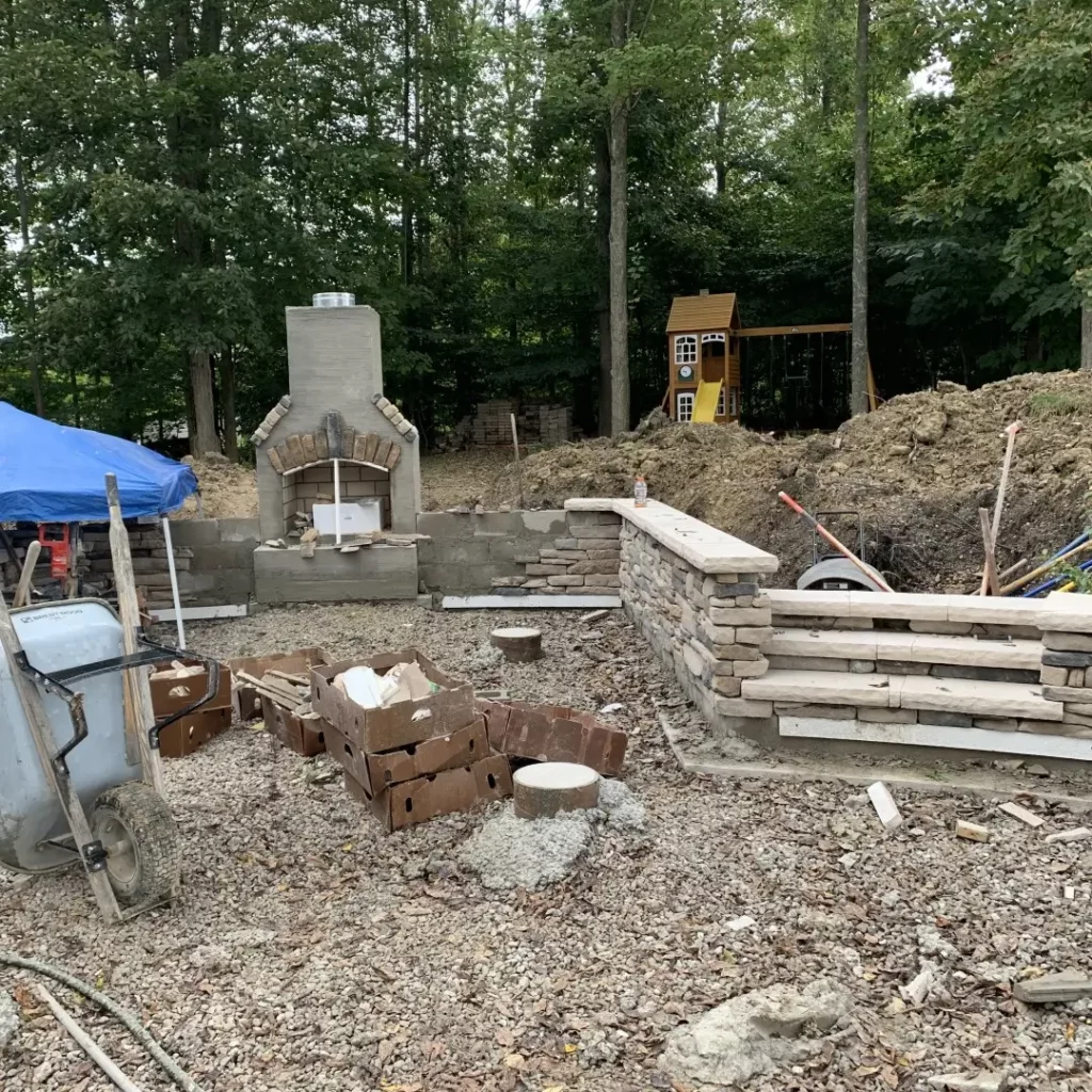 a hardscape construction site shows the building of a fireplace and veneer in preparation for a full patio installation