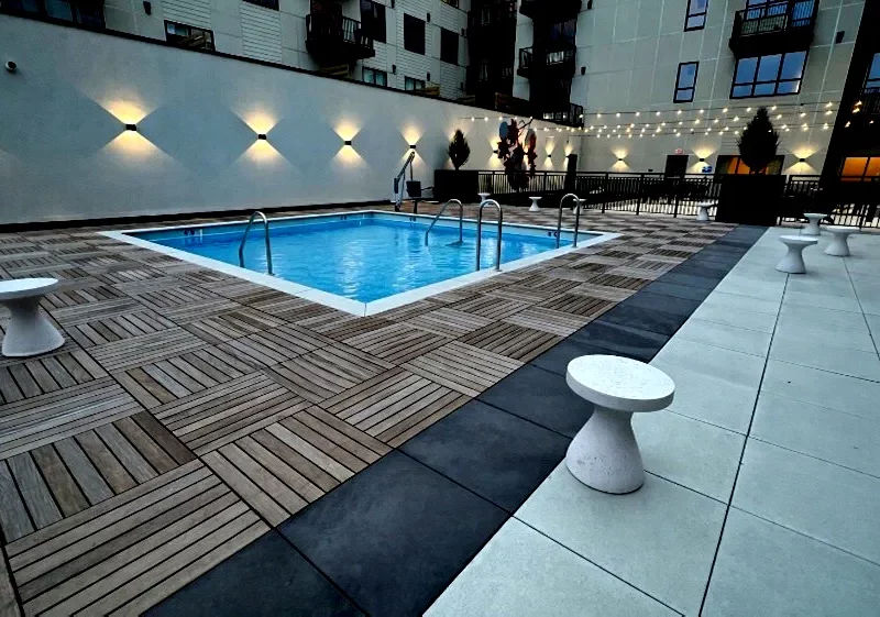 A pool deck and patio using wood and Unilock pavers installed by Carmel Landscapes a hardscape designer and outdoor living space contractor serving the Chagrin Valley and surrounding areas in Ohio.