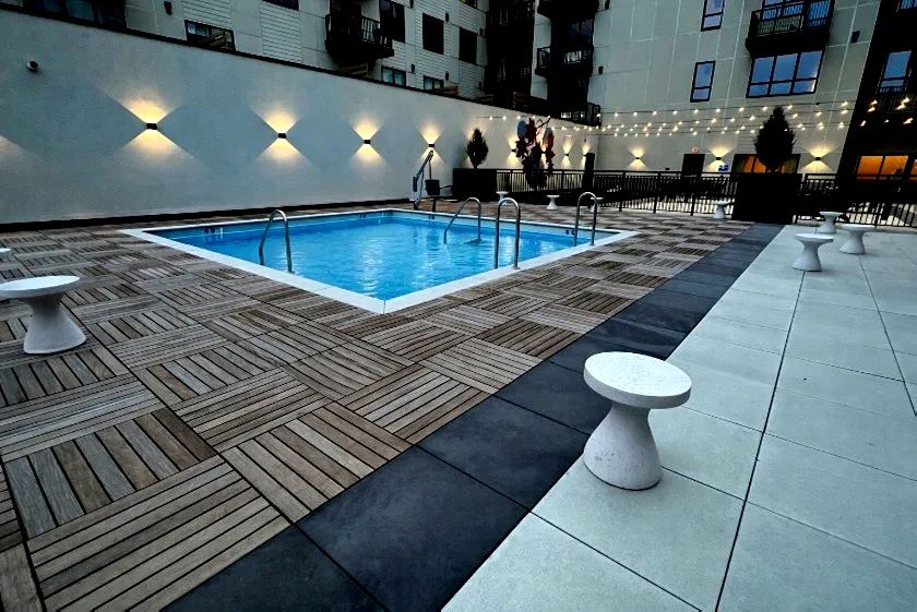 A pool deck and patio using wood and Unilock pavers installed by Carmel Landscapes a hardscape designer and outdoor living space contractor serving the Chagrin Valley and surrounding areas in Ohio.