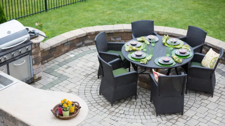 custom patio with retaining wall, outdoor countertop and sink, grill and dining table